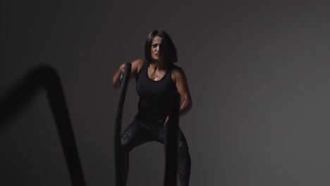Studio-Shot-Of-Mature-Woman-Wearing-Gym-Fitness-Clothing-Doing-Cardio-Exercise-With-Battle-Ropes-3